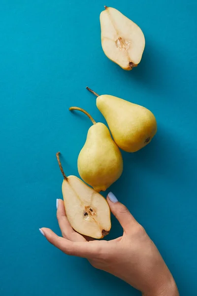 青い表面から梨の半分を取る女性の画像をトリミング — ストック写真