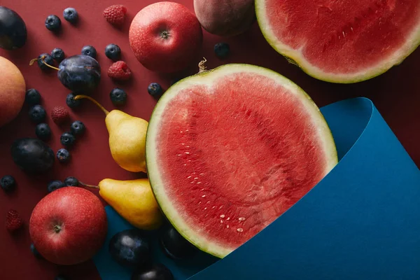 Upphöjd Syn Mogna Frukter Och Blått Papper Röd Yta — Stockfoto