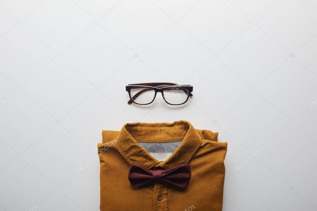 top view of brown shirt with bow tie and glasses isolated on white