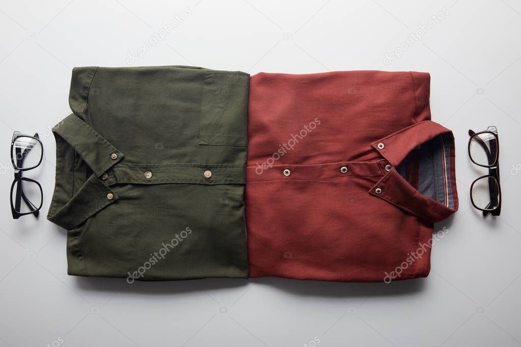 top view of two pairs of shirts and glasses isolated on white