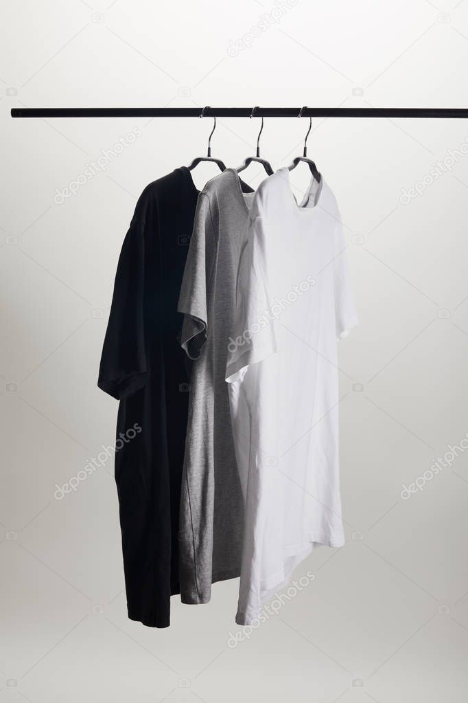 Black, grey and white shirts on hangers isolated on white