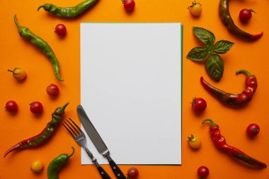 top view of blank card, cutlery and fresh tomatoes with basil and peppers on orange clipart