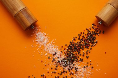 top view of spice containers and salt with peppercorns on orange clipart