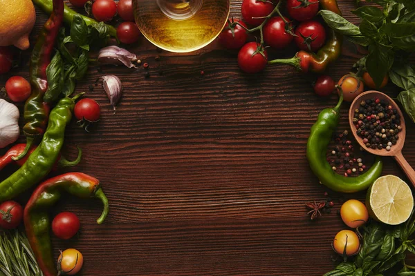 top view of oil, seasonings and vegetables on wooden background