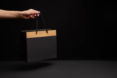 kısmi görünümünü siyah alışveriş çantası siyah zemin üzerinde tutan kadın
