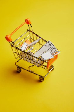 kağıt paketler sarı arka plan üzerinde elbise ile küçük alışveriş sepeti görünümünü yakın