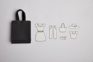 Konsept alışveriş gri arka plan üzerinde siyah alışveriş çantası ve kağıt giyim üstten görünüm
