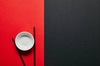 kırmızı ve siyah arka plan üzerinde görücü usulü boş kase ve yemek çubukları üstten görünüm