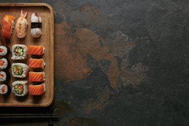 görücü usulü suşi ahşap plaka ve chopsticks karanlık yüzeyi tarih ayarla üstten görünüm