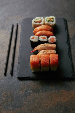 görücü usulü suşi siyah arduvaz levha ve chopsticks karanlık yüzeyi tarih ayarla görünümünü kapat
