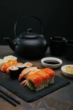 gıda kompozisyon kaseler, Çaydanlık ve bardak çay karanlık yüzeyi ile sushi set, zencefil ve soya sos ile