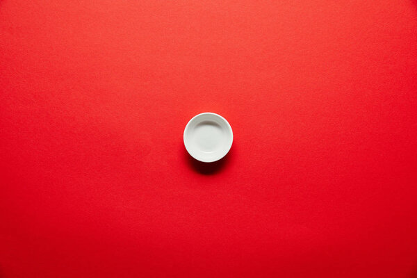 top view of white empty bowl for soya sauce on red backdrop