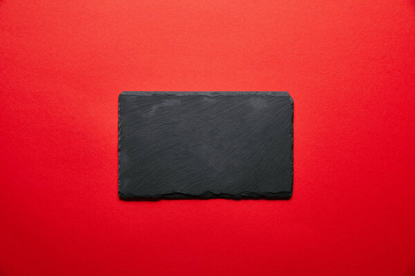 вид сверху на пустую черную табличку для суши, изолированную на красном

