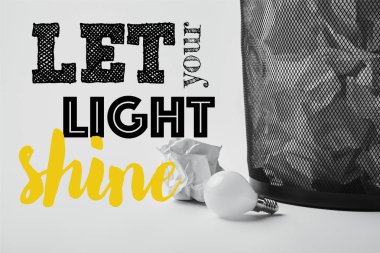 light bulb with crumpled papers in office trash bin on white with 