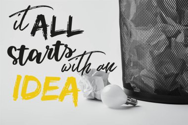 light bulb with crumpled papers in office trash bin on white with 