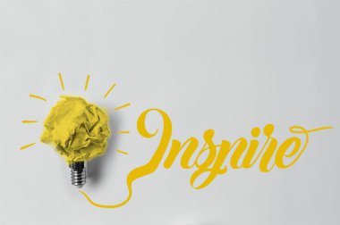 top view of crumpled paper as light bulb with inspire lettering clipart