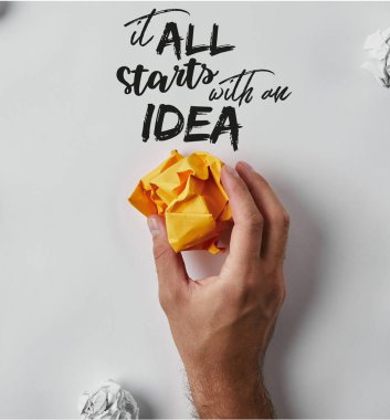 cropped shot of man holding crumpled yellow paper with 