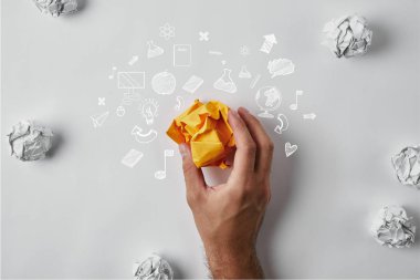 Holding adam sarı kağıt iş ikonları/simgeleri ve beyaz yüzeyi beyaz buruşuk kağıtlar ile çevrili buruşuk
