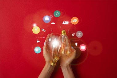 woman holding vintage incandescent lamps with business icons on red tabletop clipart