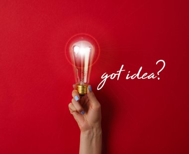 woman holding vintage incandescent lamp on red surface with 