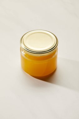 close up view of sweet organic honey in glass jar on white surface clipart