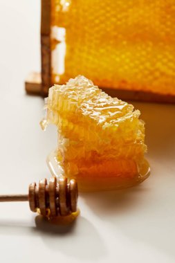 close up view of wooden honey deeper and stack of beeswax on white tabletop clipart