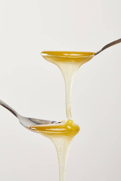 крупный план ложки с медом на белом фоне
