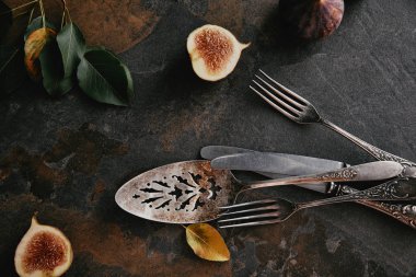 grungy yüzeyi antika çatal bıçak takımı, yeşil yaprakları ve incir üstten görünüm