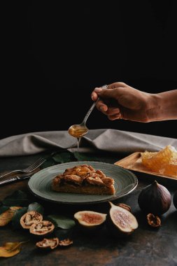 Ev yapımı pasta parçası üzerinde bal dökülen kadının kısmi görünümü
