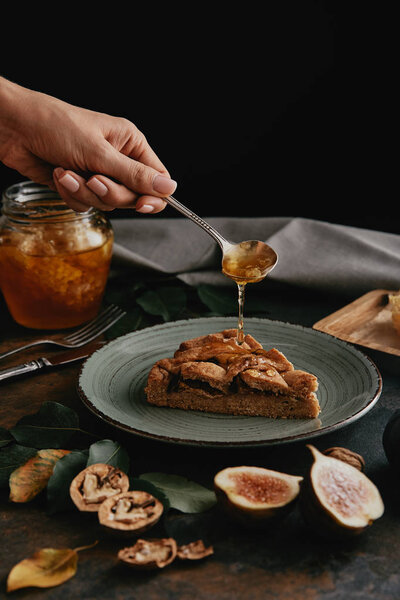 partial view of woman pouring honey on piece of homemade pie