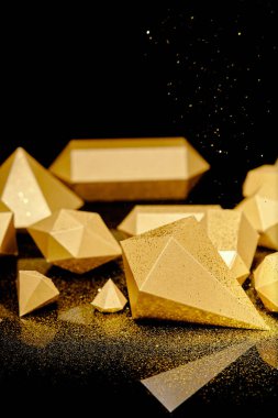 close-up view of shiny glittering pieces of gold and golden dust on black  clipart