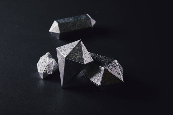 high angle view of shiny faceted silver pieces on black    