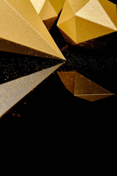 close-up view of glittering faceted pieces of gold reflected on black background