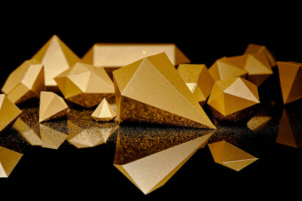 close-up view of shiny pieces of gold and golden dust reflected on black   