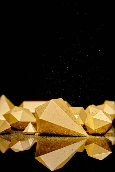 shiny glittering pieces of gold and golden dust reflected on black background 