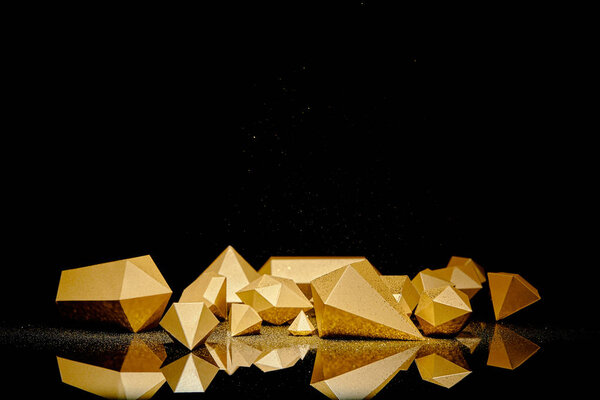 shiny faceted golden pieces and dust reflected on black background 