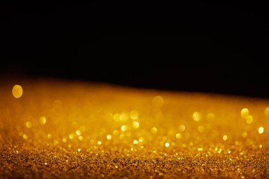 blurred golden glowing glitter on black background clipart