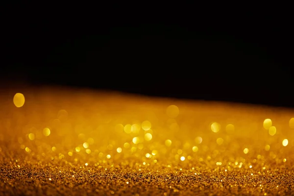 blurred golden glowing glitter on black background