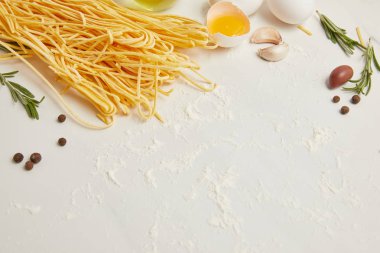 Düzenlenmiş pişmemiş makarna, çiğ tavuk yumurtası ve sarımsak yemek makarna için bakış beyaz yüzey üzerinde kapatın