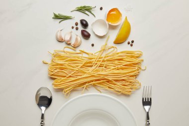 beyaz mermer yüzeyindeki boş plaka ve makarna malzemelerle düz lay