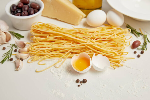  close up view of arranged ingredients for cooking italian pasta on white tabletop
