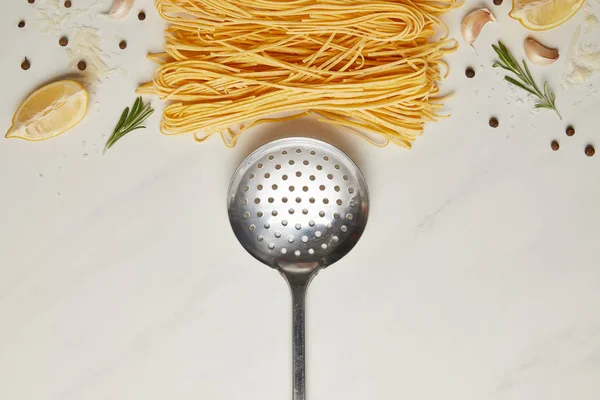 白色大理石桌面上的钢包和意大利面食配料的顶级视图 — 图库照片