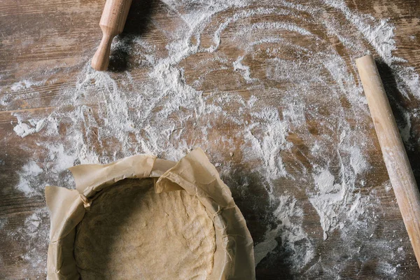 parşömen kağıt üzerine un ile kaplı rustik ahşap masa ile fırın tepsisi