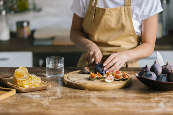 cropped shot of woman cutting figs for pie on rustic wooden table