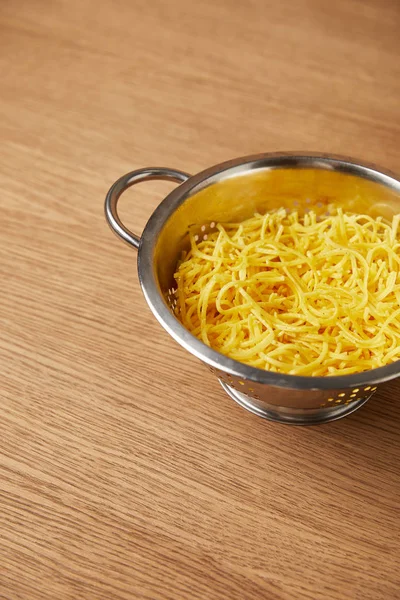 Hög Vinkel Syn Metall Durkslag Med Spaghetti Träbord — Gratis stockfoto