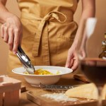 Schnappschuss von Frau, die Spaghetti mit Zange in Schüssel steckt Schnappschuss von Frau, die Spaghetti mit Zange in Schüssel steckt