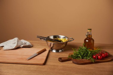 Spagetti sebze ve zeytinyağı ahşap masa üzerinde metal kevgir içinde