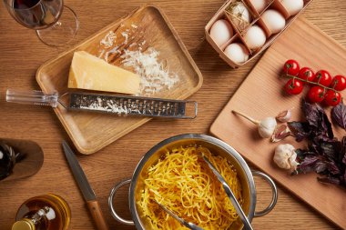 spagetti makarna üzerine ahşap masa için çeşitli malzemeler ile çevrili metal kevgir içinde üstten görünüm