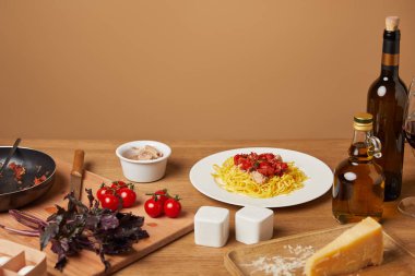 plate of pasta with various ingredients and wine around on wooden table clipart