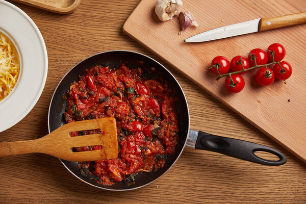 top view of frying pan with tomato sauce for pasta on wooden table